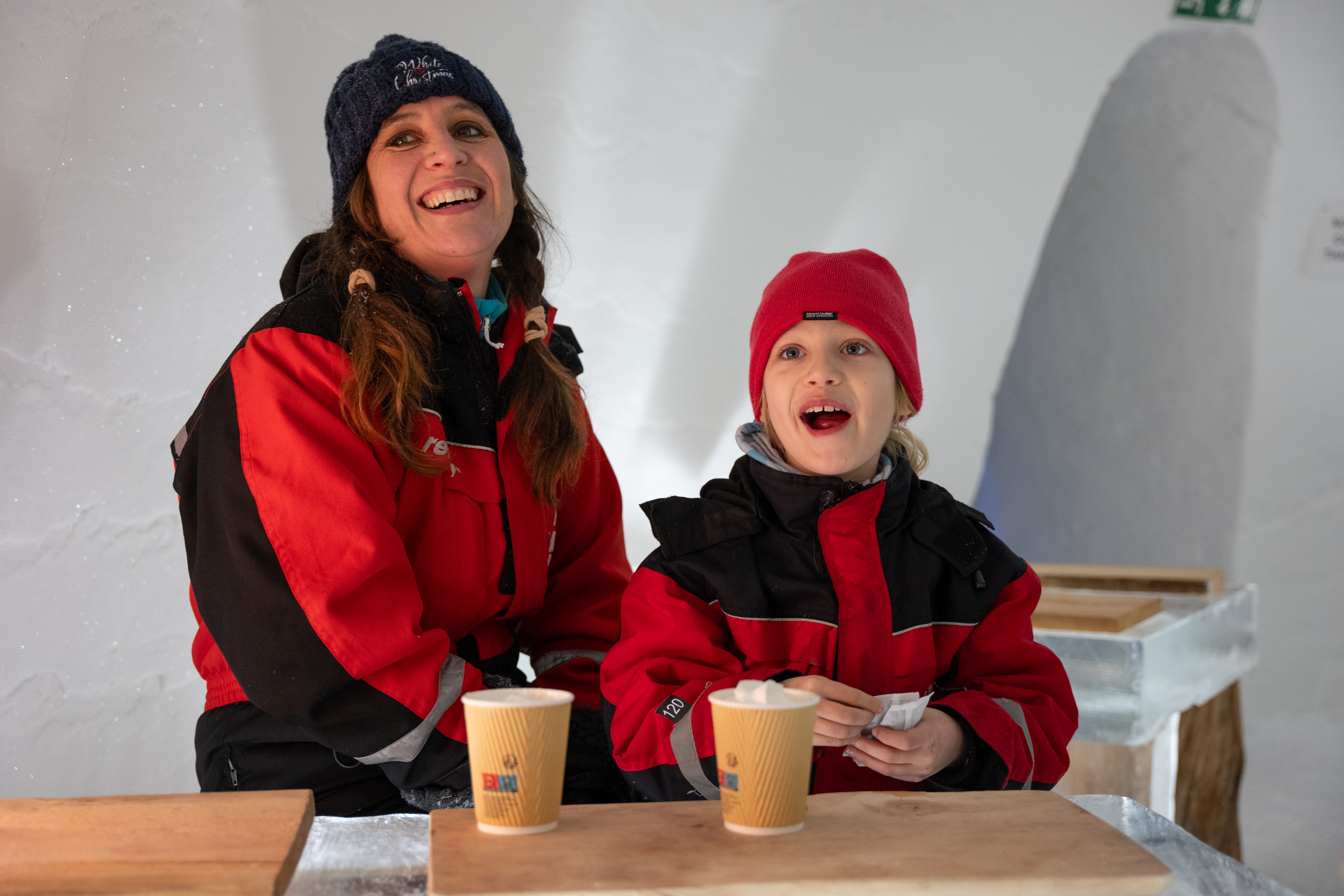 Parent and child smiling inside the igloo on a Santa’s Magic Lapland short break.