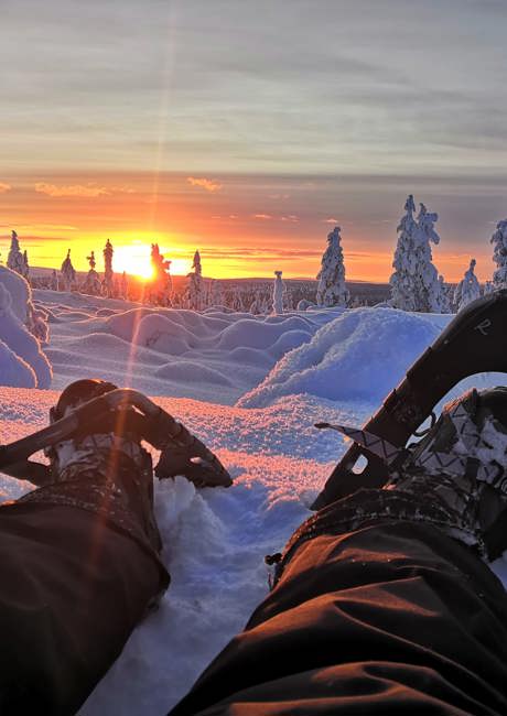 sitting in snowshoes at sunset