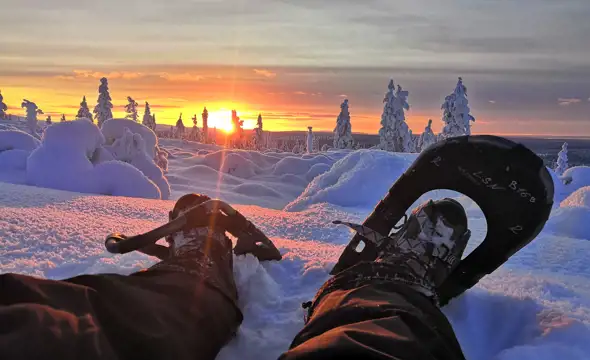 sitting in snowshoes at sunset