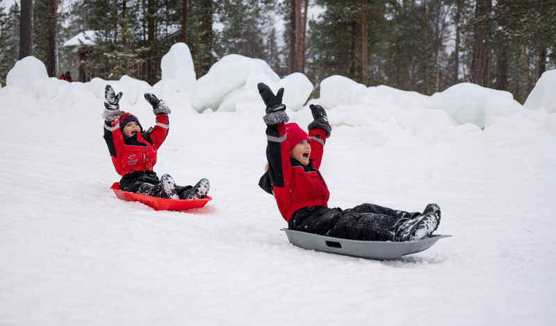 Children tobogganing in the snow on a Santa’s Magic Lapland holiday.