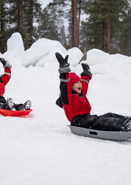 Children tobogganing in the snow on a Santa’s Magic Lapland holiday.
